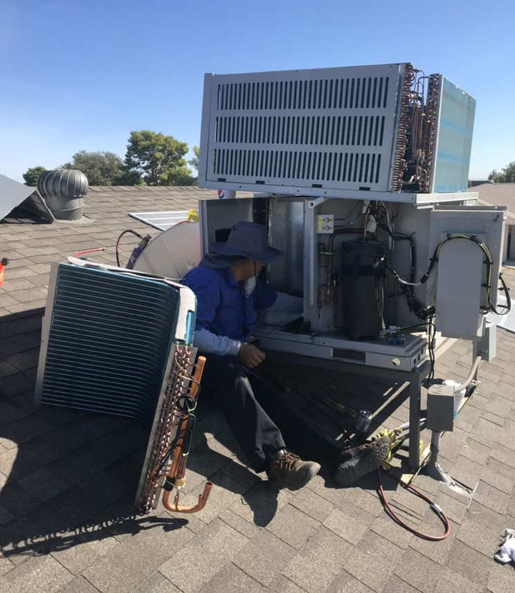 Technician repairing AC unit on the roof